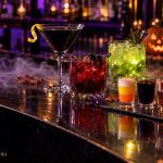 Halloween Cocktails and Shots: Spooky Drinks for Your Party Halloween cocktails and layered shots on a dark bar with a glowing jack-o-lantern